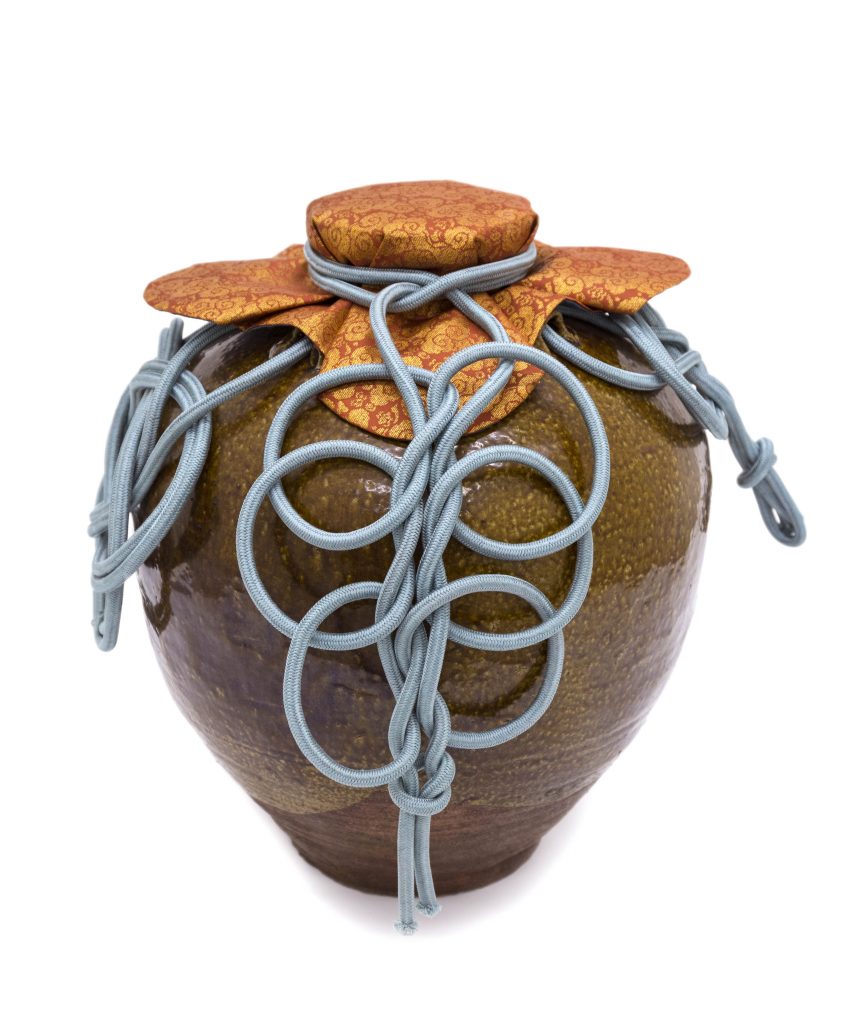 Tea-leaf storage jar named Chigusa with mouth cover and ornamental cords. Photo credit: Courtesy Freer Gallery of Art. The mouth cover for Chigusa was made by Tsuchida Yuko in 2013; the cords for tying ornamental knots are from the Japanese Meiji era (late 19th–early 20th c.)