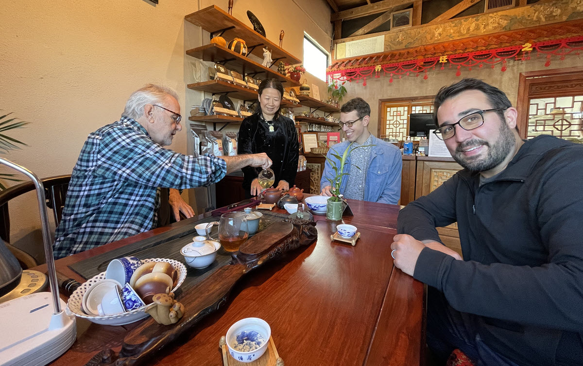 Owners Austin Hodge (serving tea) and Zhuping Hodge, center.